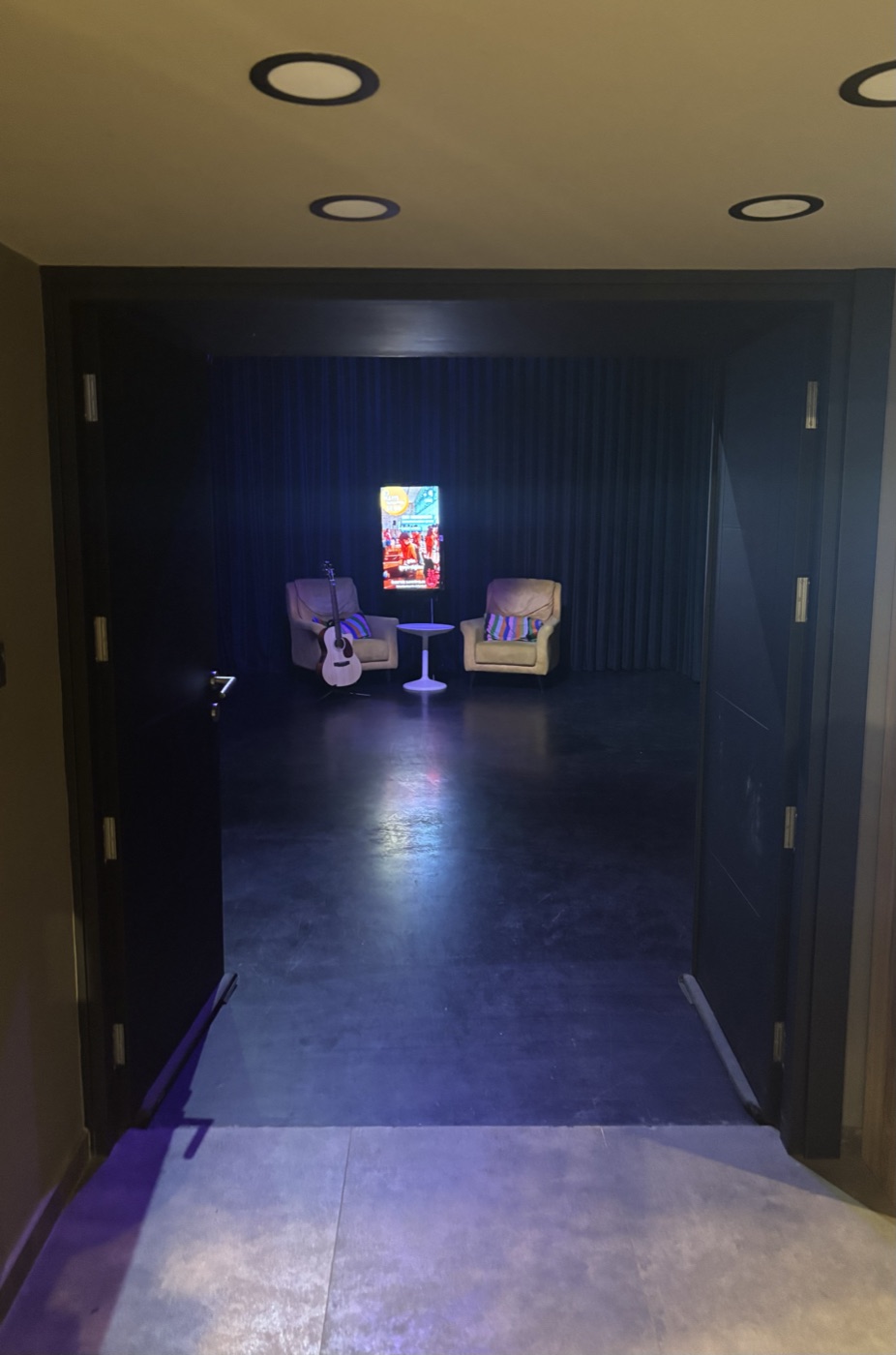 Lounge girişi — loş ışıkta koltuklar ve gitar